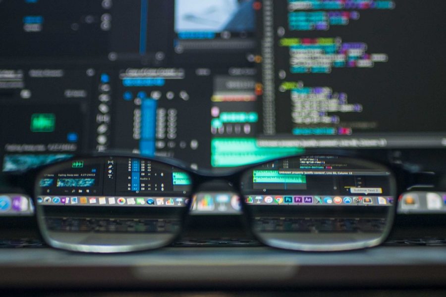 brille vor zwei monitoren mit code